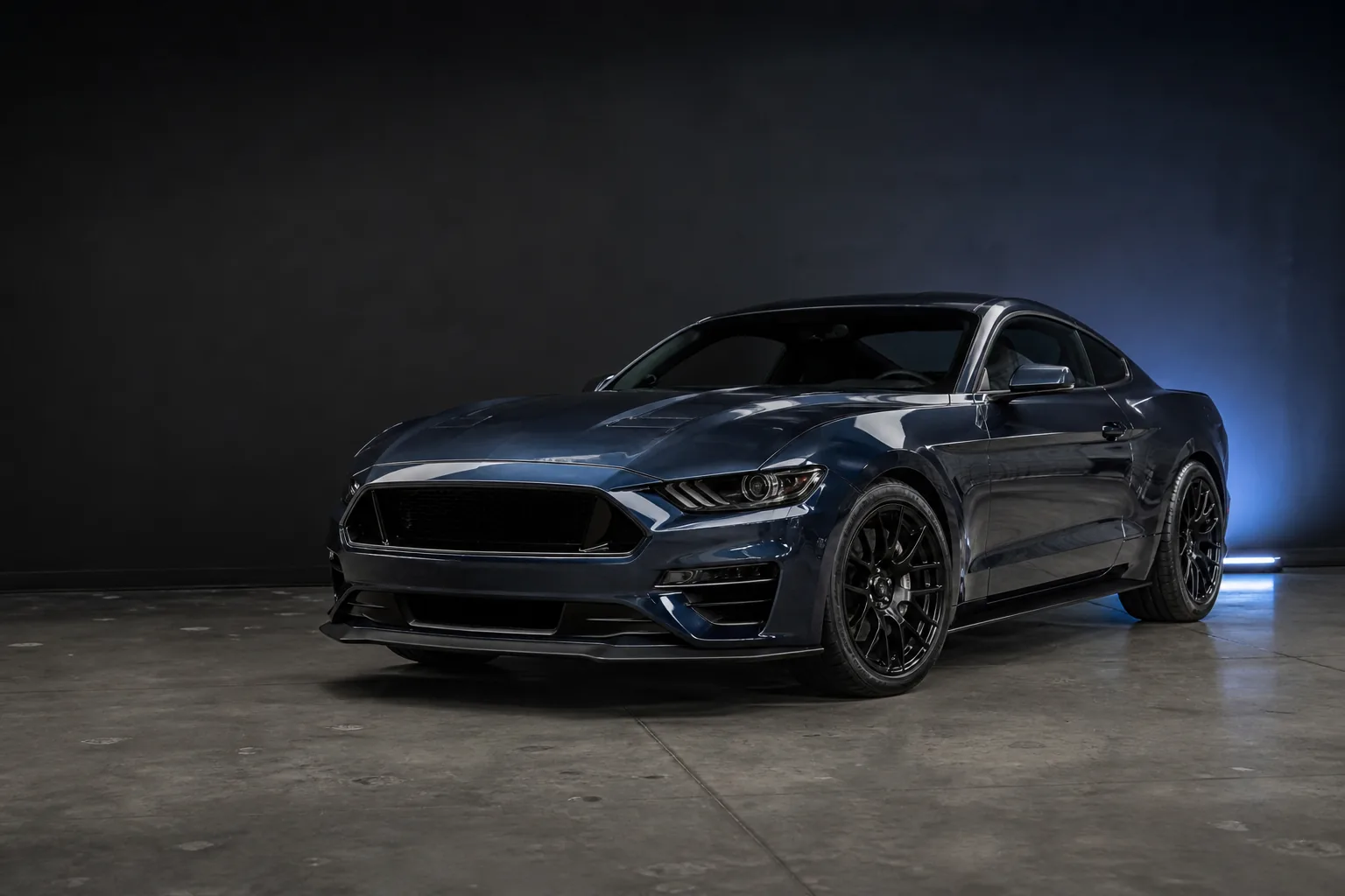Dark metallic blue Mustang fastback photographed in a professional automotive studio